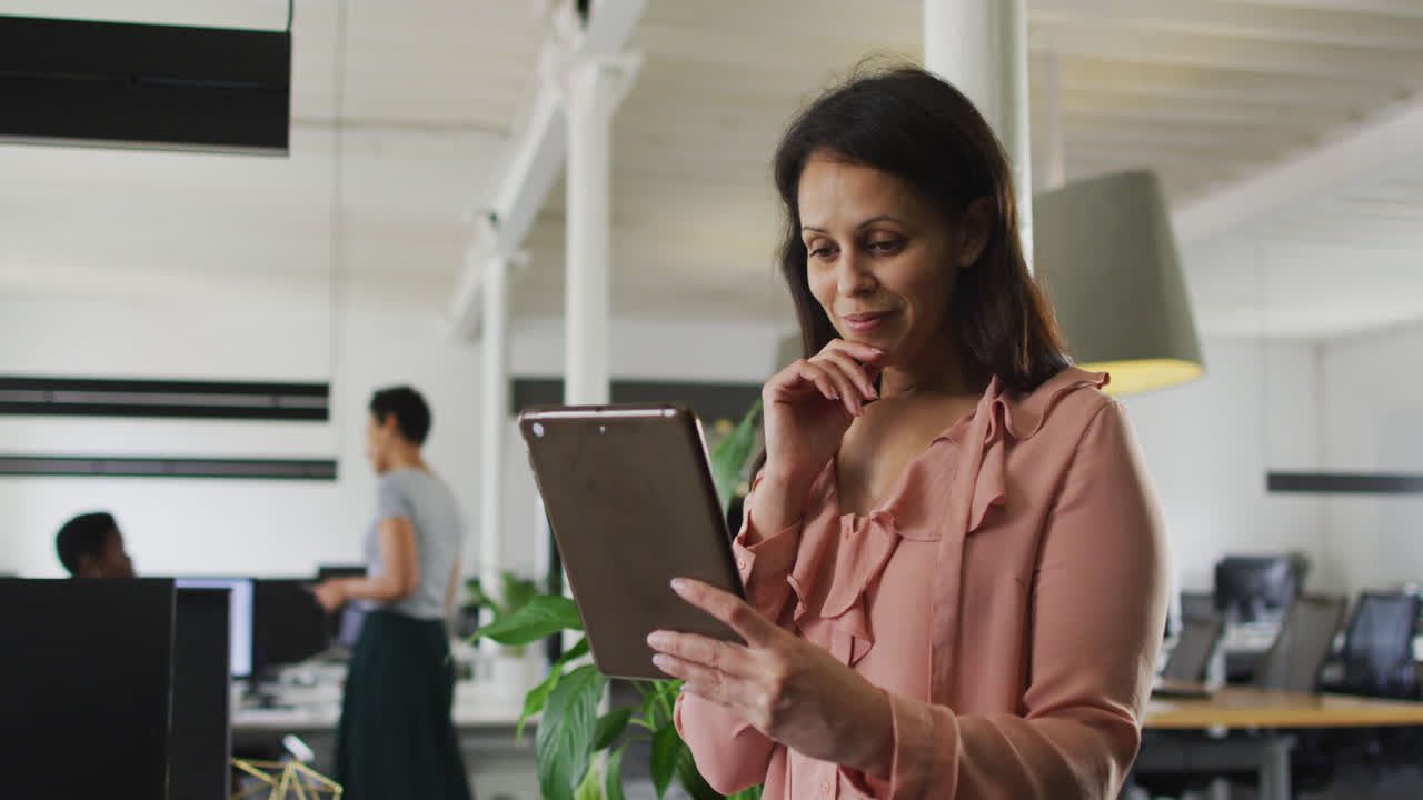 mujer de negocios caucásica sonriente trabajando en una tableta en la oficina