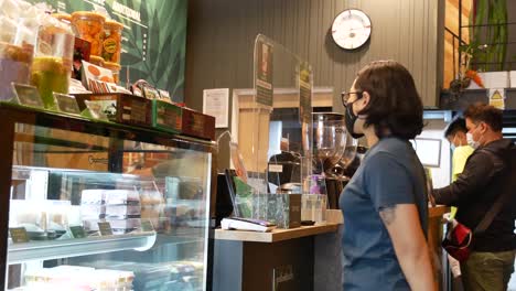 people wearing face mask buying and waiting for their orders in coffee shop