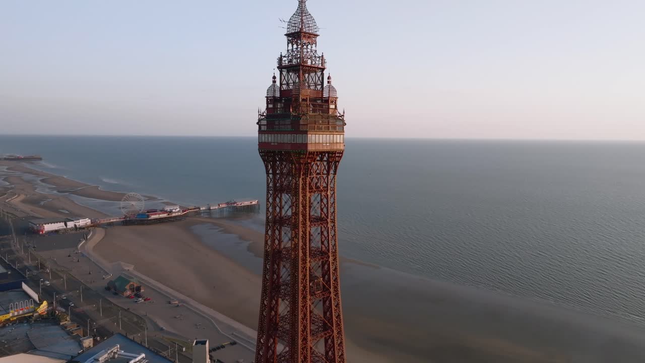 Blackpool Tower slow flight towards observation deck with beach and piers visible at golden hour. Lancashire, UK.