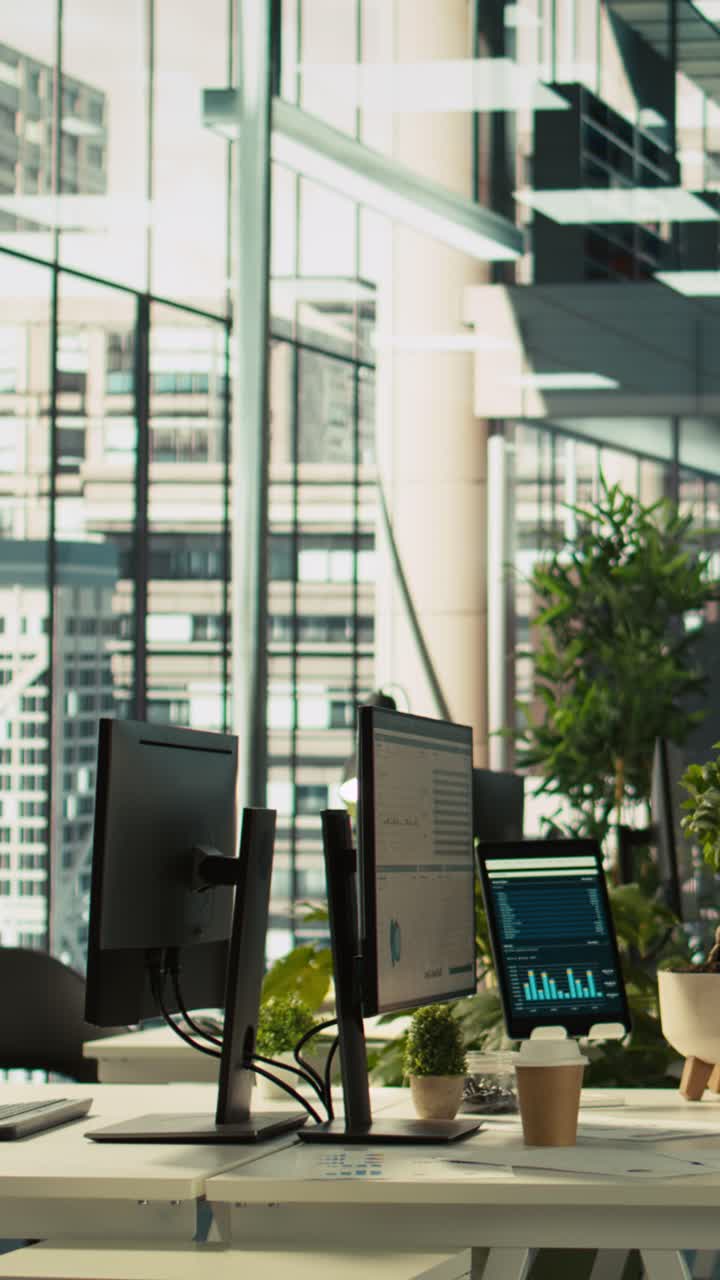 Vertical video Modern office workspace desk with computer monitors displaying graphs