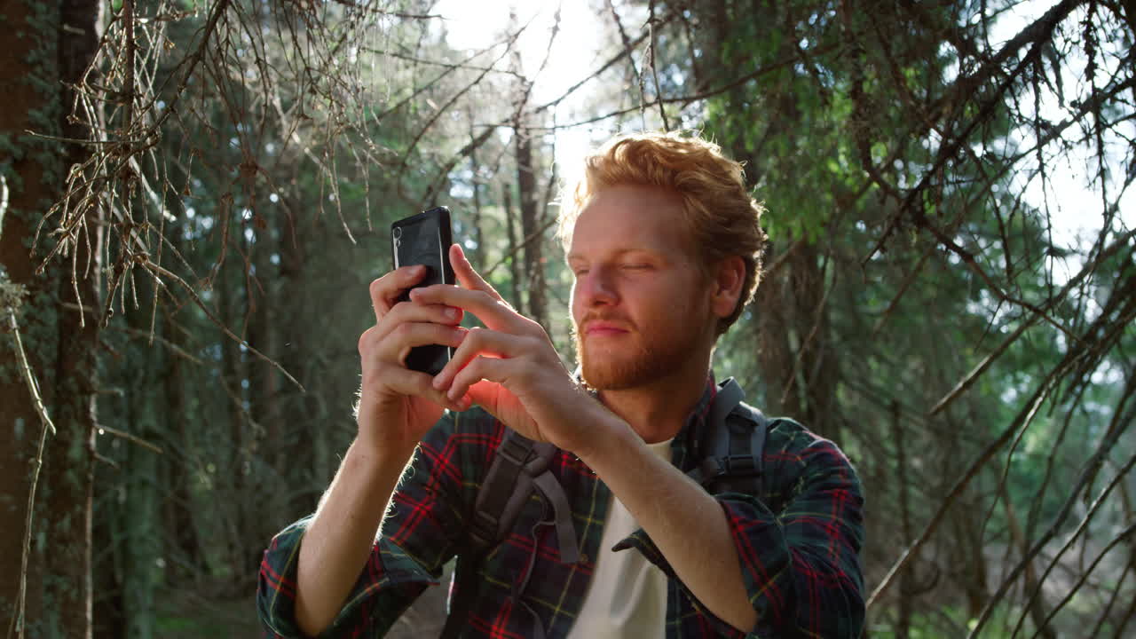 Man taking photo on smartphone in forest. Guy using mobile phone in woods.