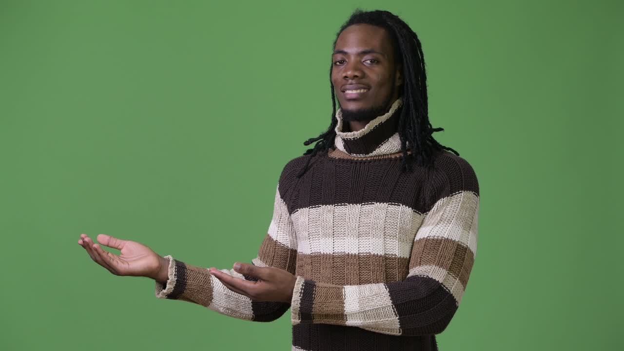 Young handsome African man with dreadlocks against green background
