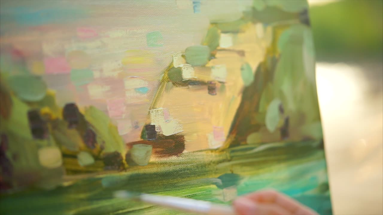 Close-up view of artist painting a landscape on canvas