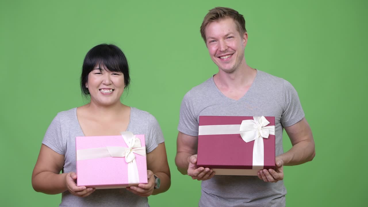 Young happy multi-ethnic couple holding gift box together