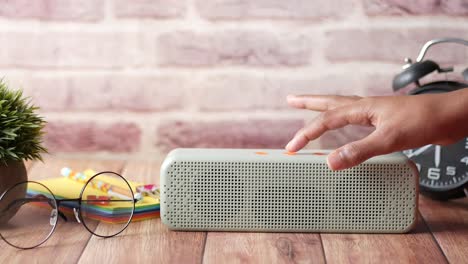 botón de toque de la mano en un altavoz inteligente en un escritorio