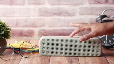 hand touching button on a smart speaker on a desk