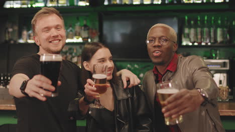 cheerful friends with beer glasses at bar