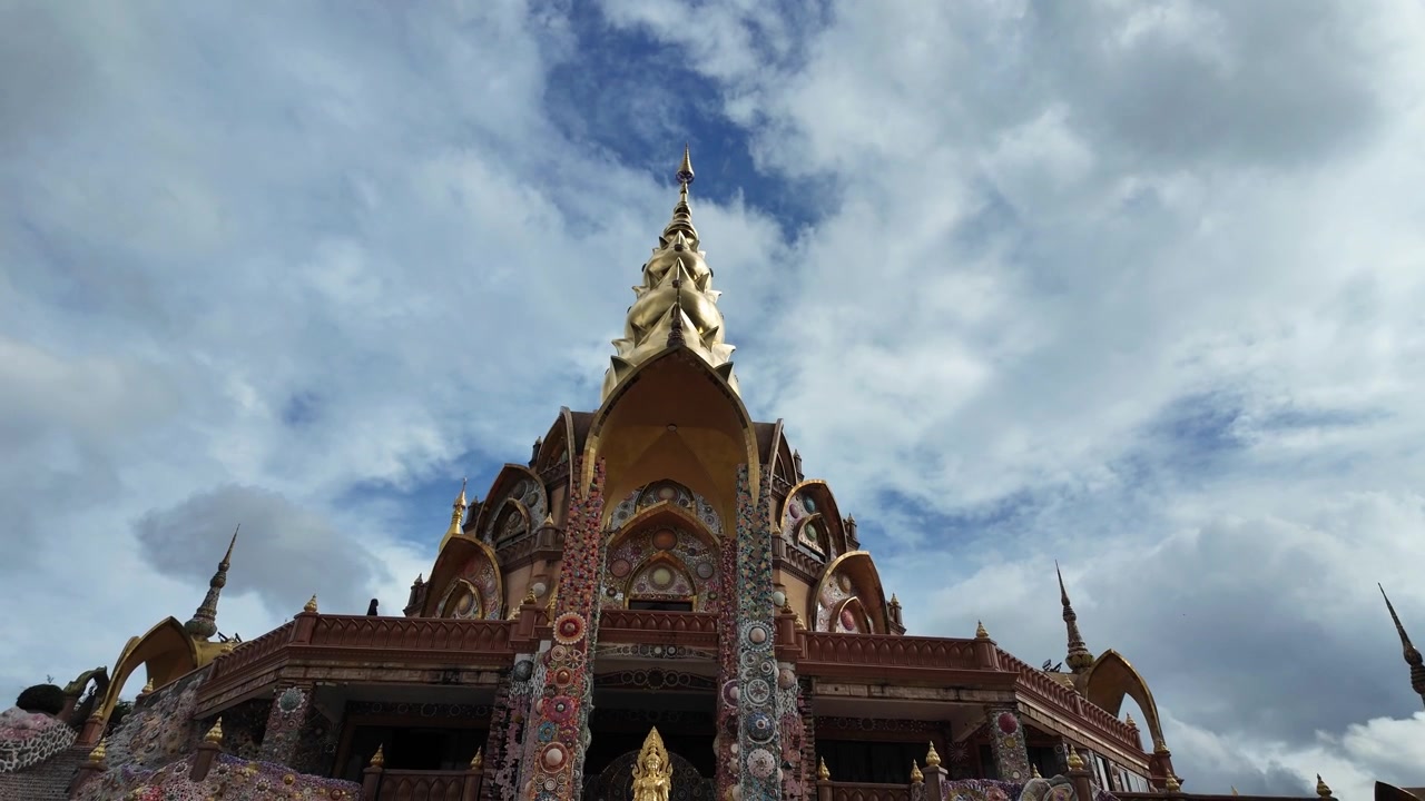 Splendida ripresa dal basso della grande pagoda dorata presso il tempio Wat Pha Sorn Kaew a Phetchabun, Thailandia. Mette in mostra una magnifica architettura a mosaico sotto un cielo luminoso con nuvole bianche di passaggio