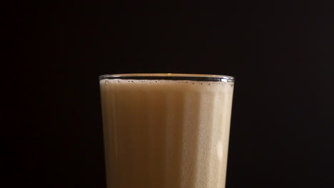 Beer-foam-bubbling-into-a-transparent-glass,-close-up-slow-motion