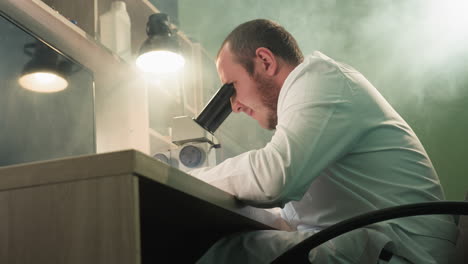 a close-up view of a technician in a lab coat meticulously working under a microscope, inspecting an electronic circuit board, with a desk lamp on been reflected on the screen