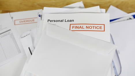 a pile of bills and letters with a final notice for a personal loan