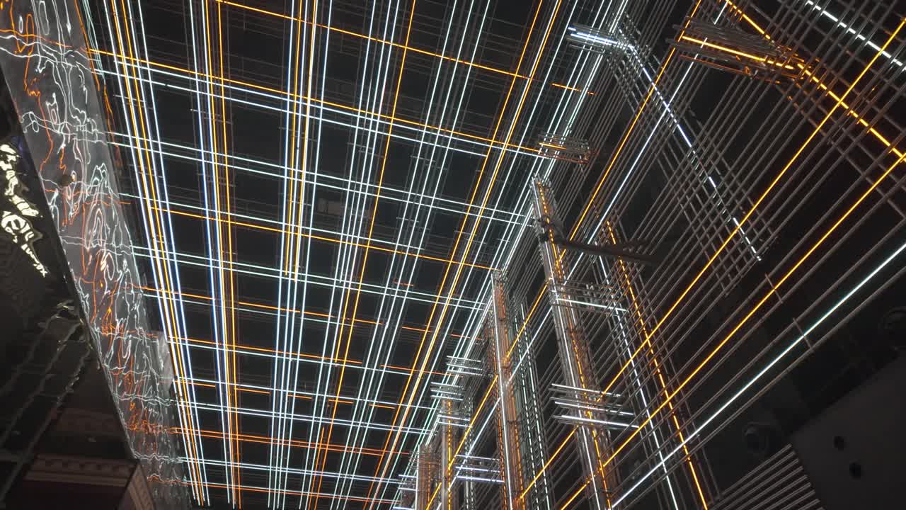 Il video mostra un moderno interno con soffitto nel centro commerciale Chengdu Global Center, con una griglia di linee luminose a LED bianche e gialle che creano un motivo geometrico