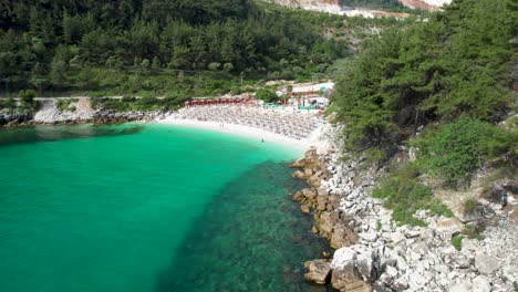 rotating aerial view revealing a white beach with turquoise water and lush green vegetation, marble beach, thassos island, greece