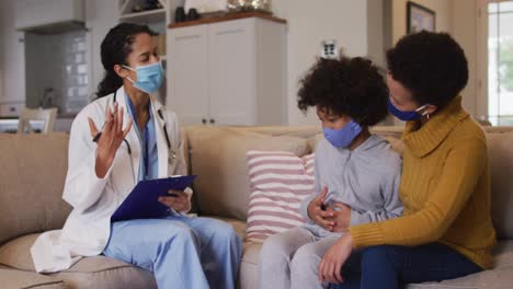 mixed race female doctor wearing mask examining mixed race girl at home