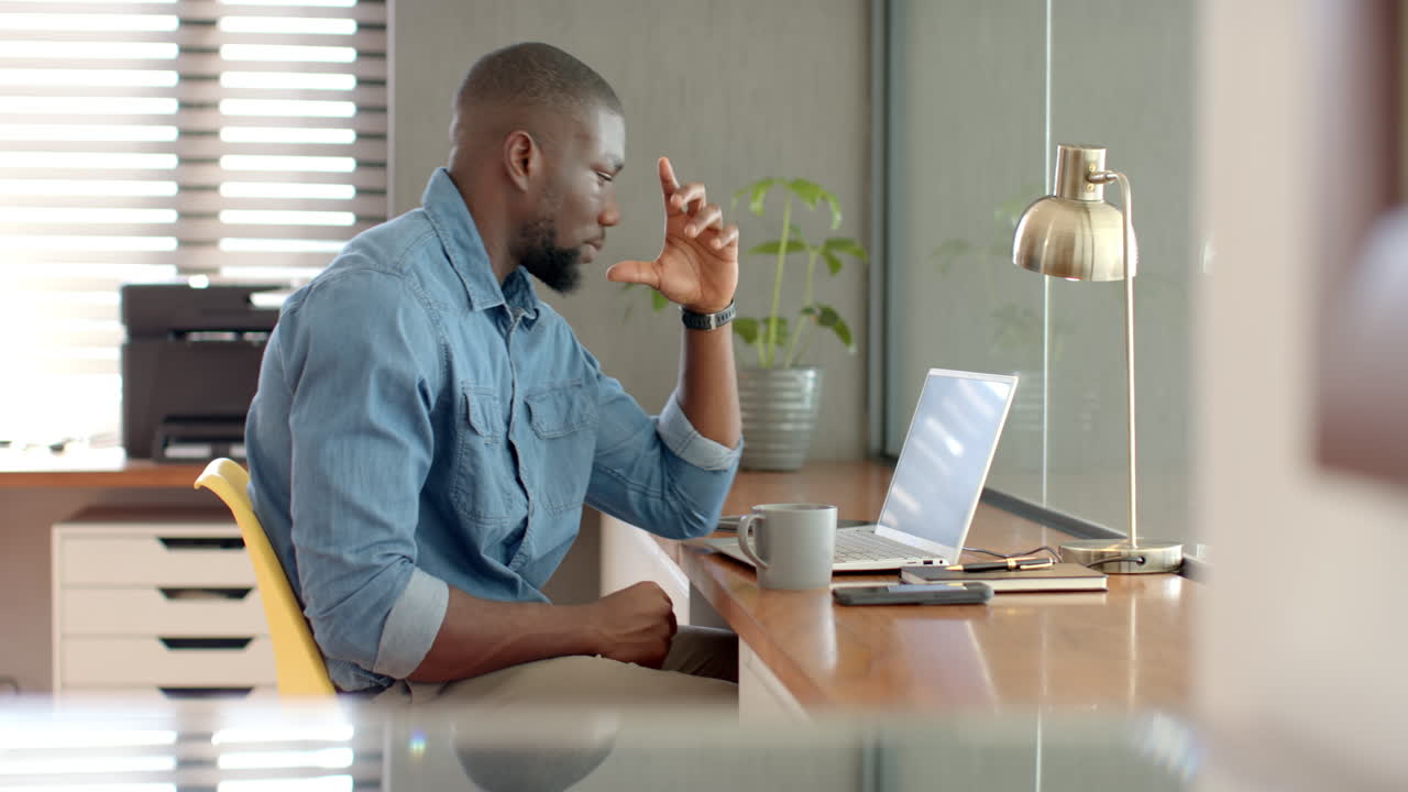 Working from home, man using laptop and looking stressed at desk