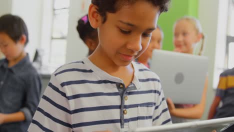 lindo escolar de raza mixta usando una tableta digital en el aula en la escuela 4k