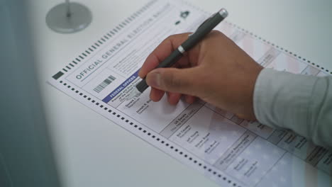 african american man choosing which presidential candidate to vote for in paper ballot close up of anonymous african american man choosing which presidential candidate to vote for in paper ballot in voting booth us citizen at polling station national elections day in united states