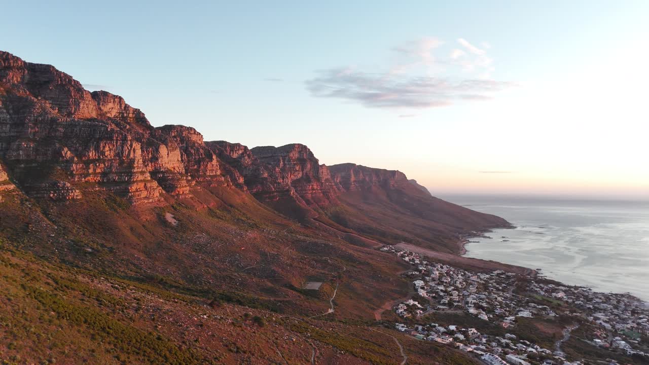 Vista aerea dall'alto angolo della spiaggia di Camps Bay a Città del Capo al tramonto con una vista mozzafiato sull'Oceano Atlantico dalle cime delle montagne
