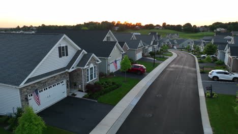 Aerial-pull-back-from-small-home-waving-American-flag-in-driveway