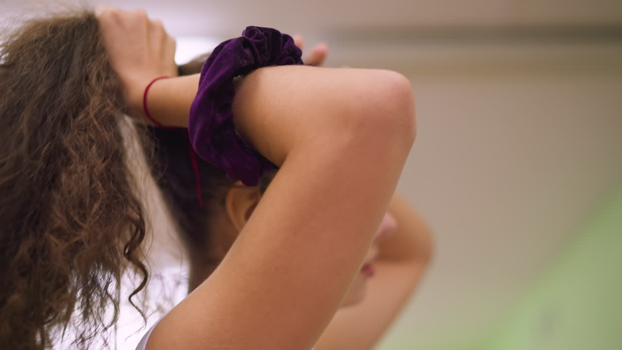 Side view of girl packing hair with hands, profile shot showing graceful motion and strand movement under soft studio light, blurred background, calm mood, natural beauty, intimate detail and texture