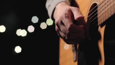 un músico está tocando la guitarra en un gran escenario con miembros de la audiencia sosteniendo linternas en el fondo. el auditorio está lleno de hermosas luces parpadeantes.