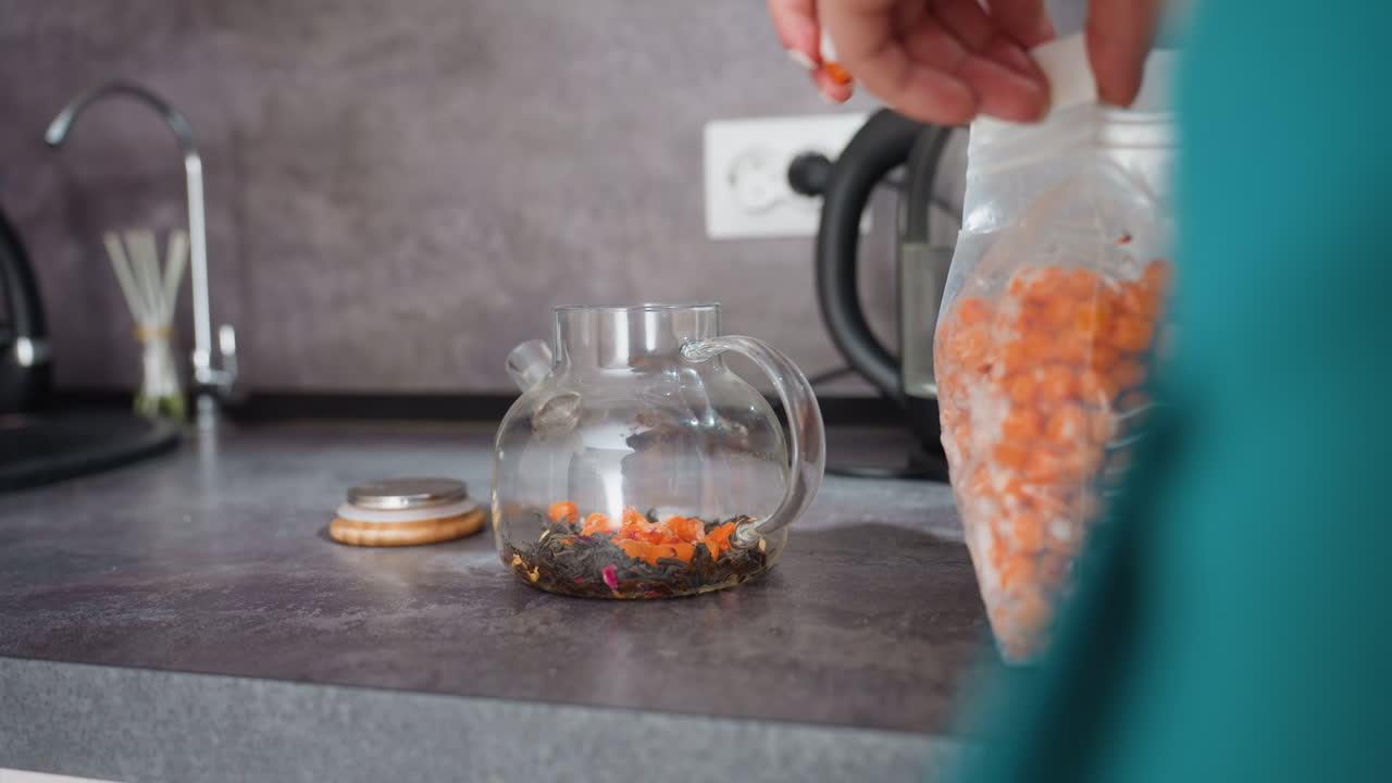 Preparazione di tisane, scena mattutina che mostra un erborista che versa delle bacche in una teiera di vetro, scena accogliente con un erborista che mette delle bacche di Goji colorate in una teiera decorata con motivi floreali al mattino
