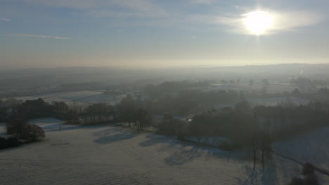 Establishing-Aerial-Drone-Shot-Forward-Over-Fields-and-Trees-in-Winter-on-Frosty-Morning-in-UK