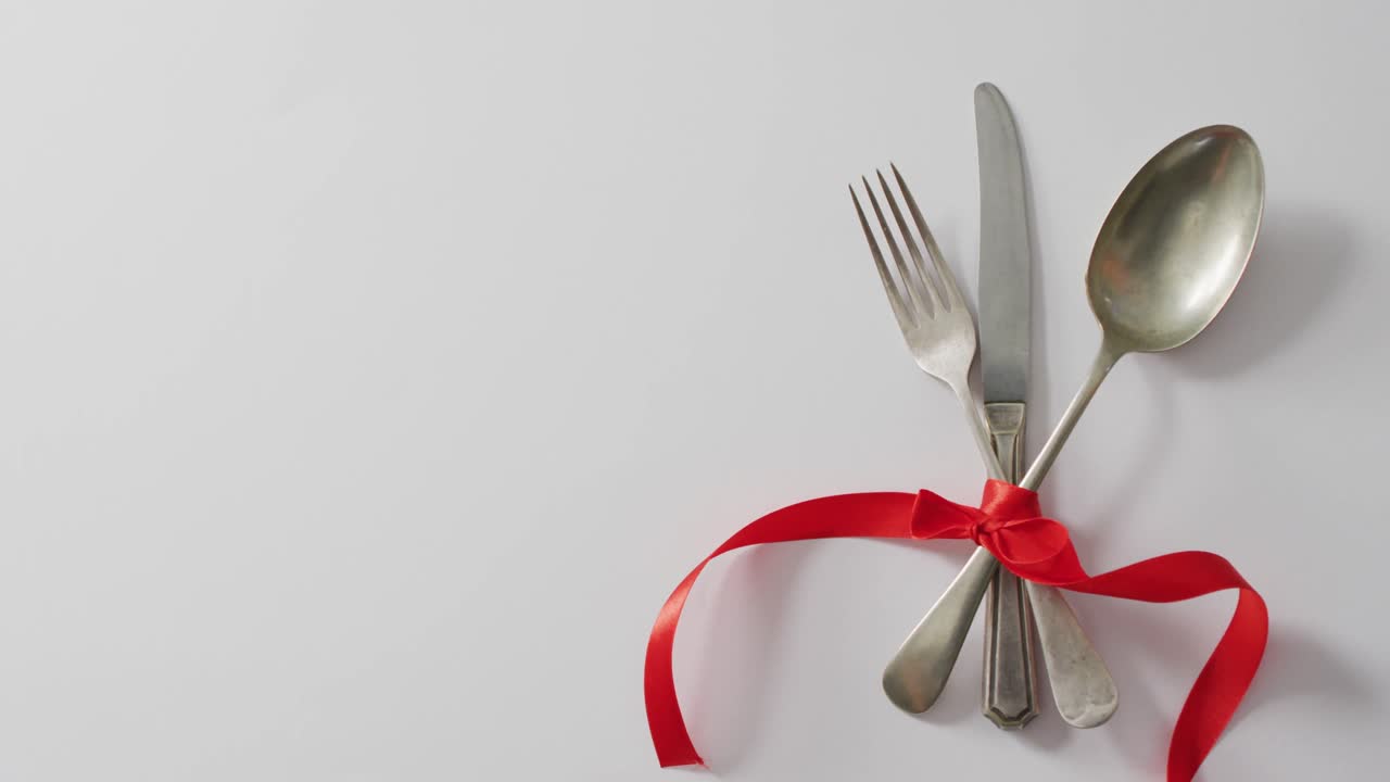 Cutlery and red ribbon on pink background at valentine's day