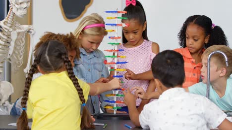 Front-view-of-Mixed-race-schoolkids-studying-about-dna-molecule-model-in-the-classroom-4k