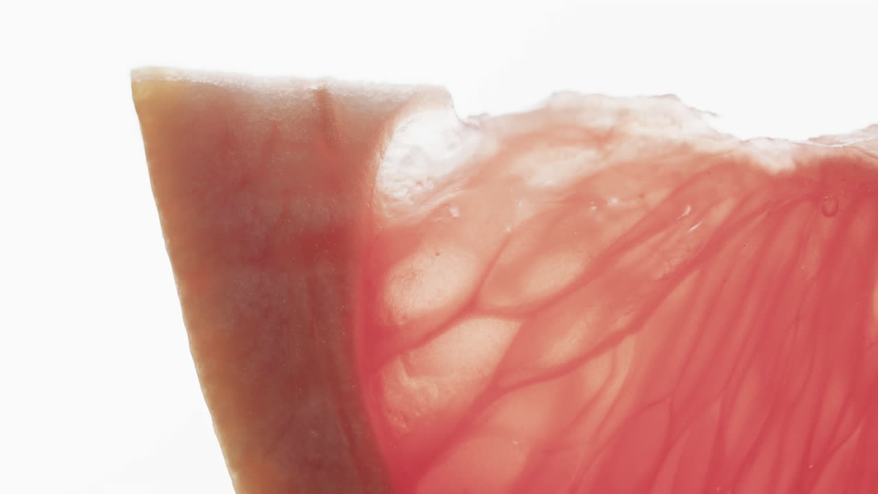 micro vídeo de primer plano de una rebanada de pomelo rojo con espacio de copia sobre fondo blanco