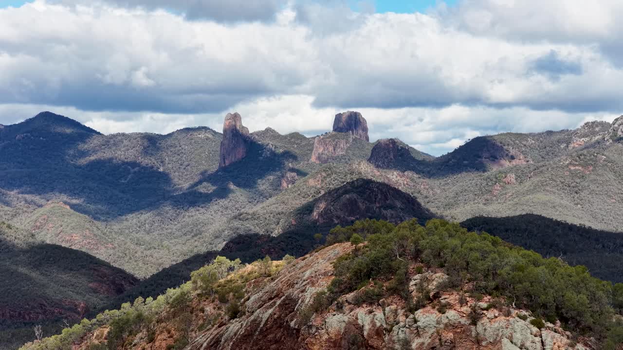Wide landscape view of the Warrumbungle mountains with rocky outcrops and bushland, captured in natural daylight with slow horizontal camera pan