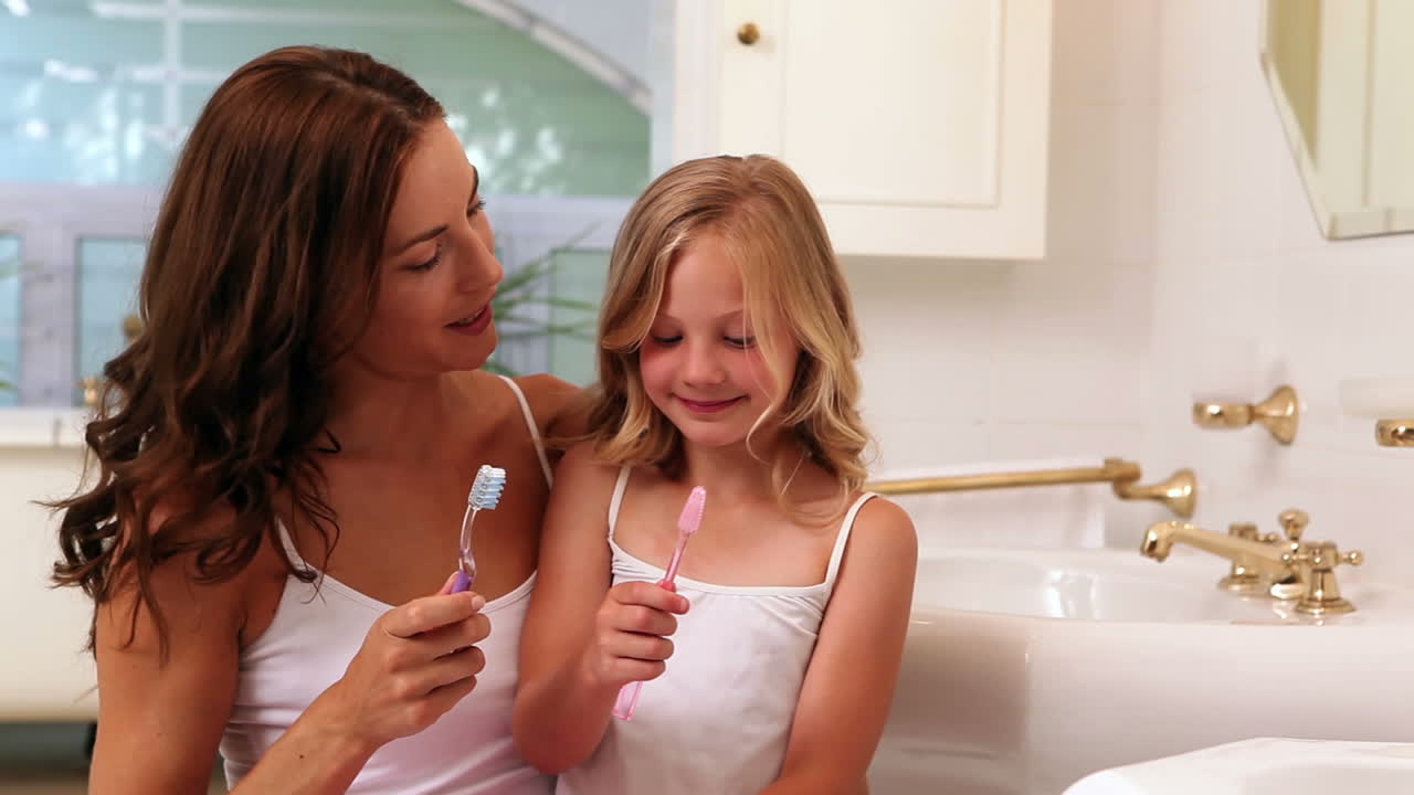 Mother and daughter brushing their teeth