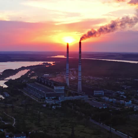 ecological disaster. harmful factory near the river releases dirty emissions at sunset. industry pollute the environment. pipes with smoke on beautiful nature background.