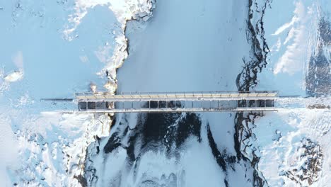 aerial of bridge between continents in iceland covered in white snow