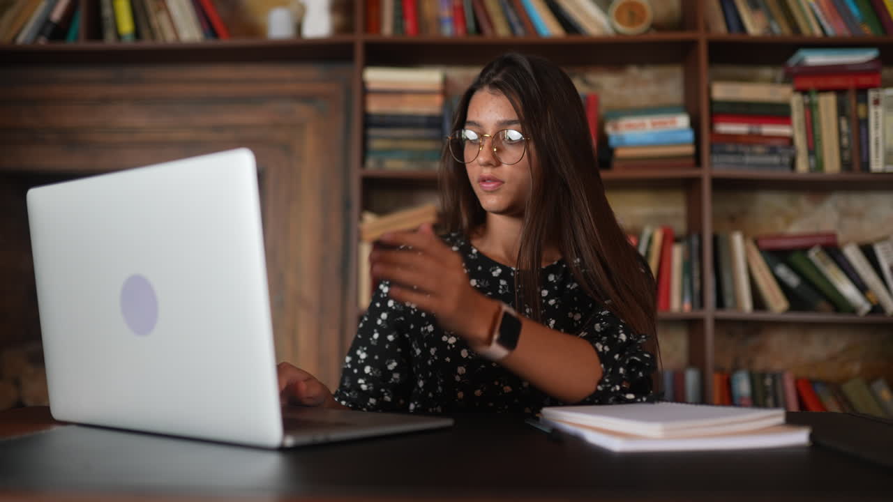 mujer joven trabajando en una computadora portátil en la biblioteca