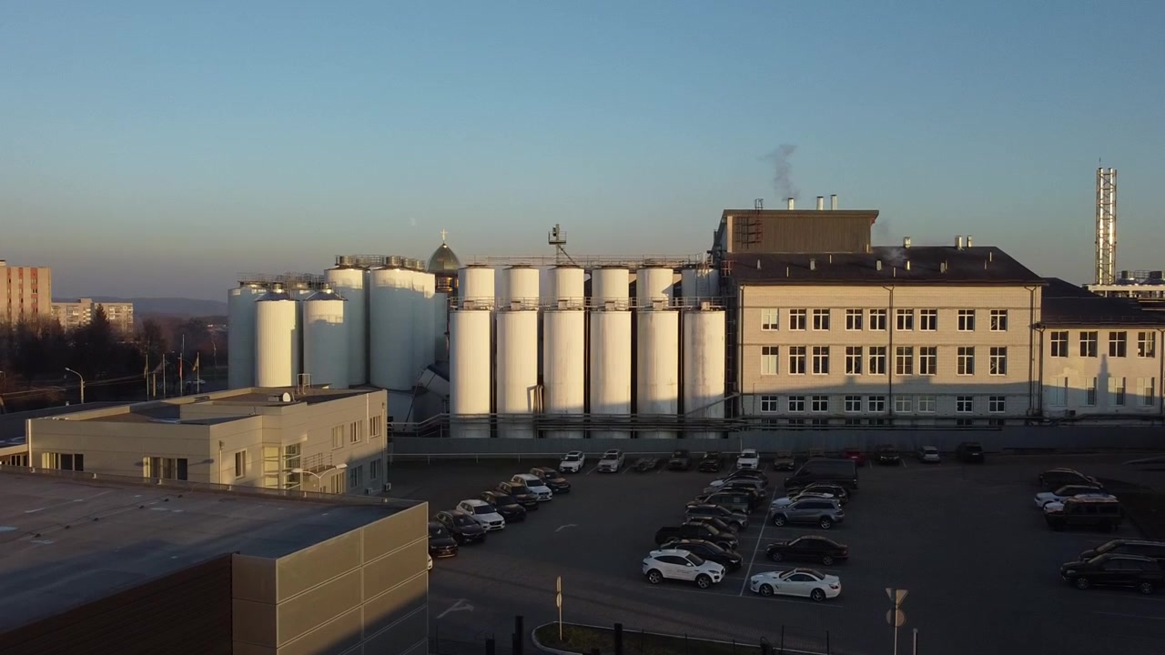 Luftaufnahme einer Drohne, die über eine Bierproduktionsanlage fliegt, mit mehreren Tankreihen.