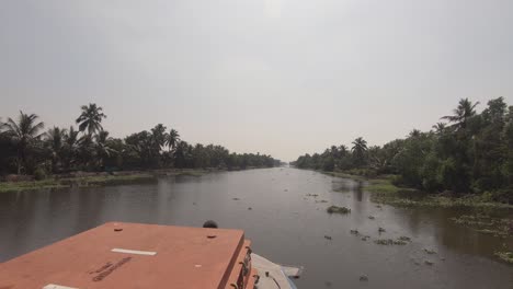 Pov-boat-trip-along-tropical-riverbanks-in-Alappuzha,-peaceful-journey-in-Kerala-waterway