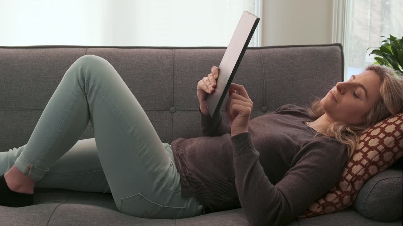Attractive young woman scrolling through her tablet