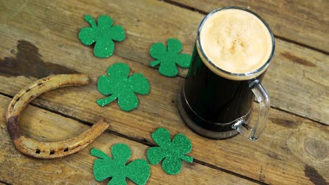 Bird eye view of guinness pint, horse shoe and shamrocks on table for st patricks