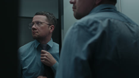 a sad man puts on his tie