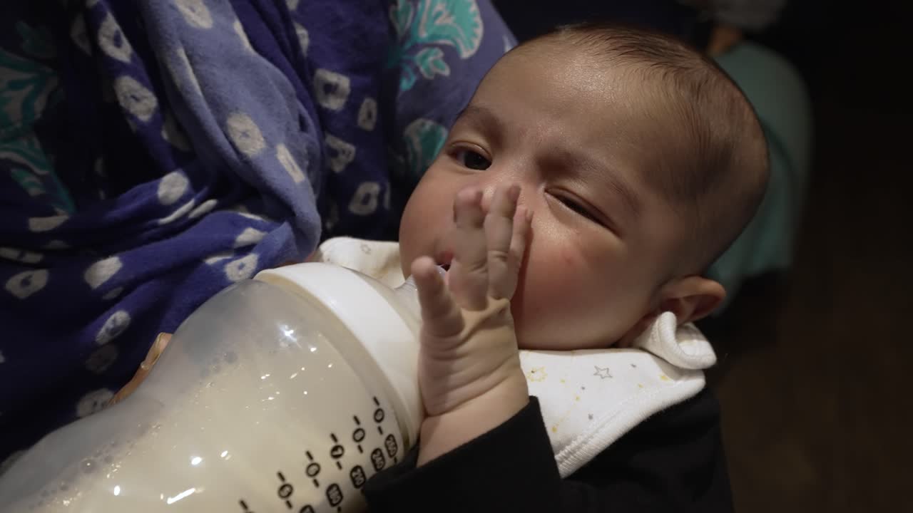 adorable bebé indio de 2 meses empujando el biberón de leche lejos de sus labios