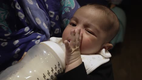 adorable 2 month old indian baby pushing bottle milk away from his lips