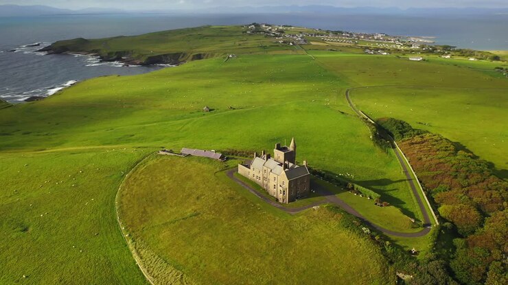 Castello di Classiebawn in suggestivo paesaggio costiero rurale in Irlanda, ripresa aerea in allontanamento