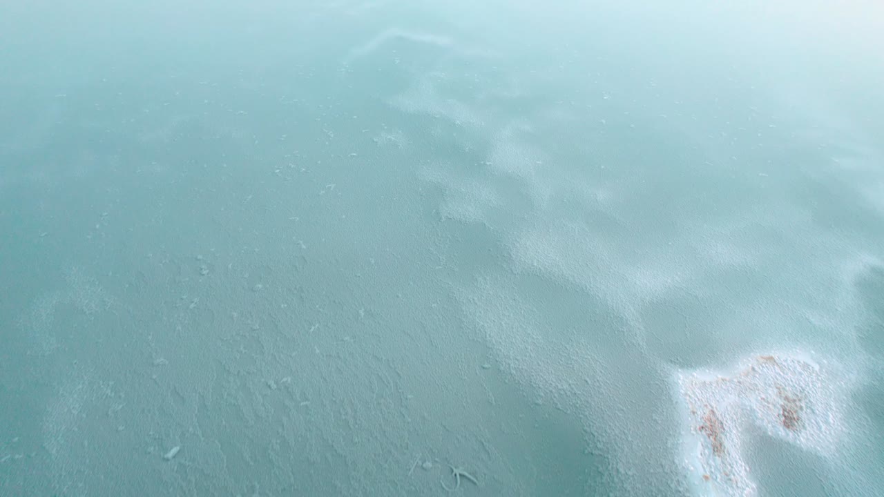 Drone captures rare frozen seascape in Hawaii from above, revealing icy patterns on the ocean's surface against the backdrop of the island's stunning coastline