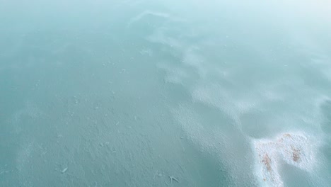 drone captures rare frozen seascape in hawaii from above, revealing icy patterns on the ocean's surface against the backdrop of the island's stunning coastline