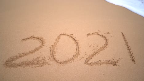 2021 written on the sand is getting washed away by the wave