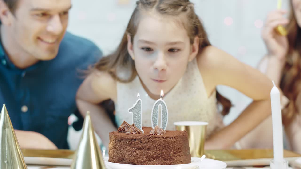 retrato de una chica sonriente soplando velas de cumpleaños en una casa de lujo.