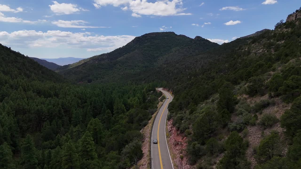 Aerial View of Small Car Driving on Highway Surrounded by Tall Green Pine Trees in the Mountains, Highway 89Ain Arizona