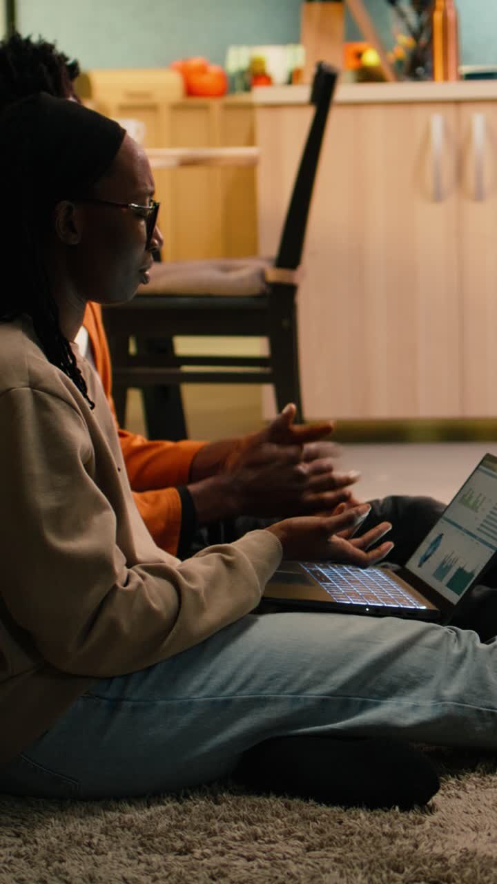Vertical Video Black people reviewing data analytics on charts from their cozy home