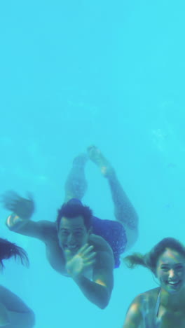 four friends jumping into swimming pool and waving